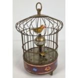 A brass ornamental wind up birdcage clock with winding mechanism to underside and red cloisonne