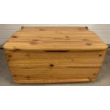 A vintage pine storage box with hinged lid and bun feet. Approx. 38cm x 72.5cm x 46cm.