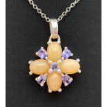 A modern design circular style orange opal and tanzanite pendant on an 18" fine belcher chain. By