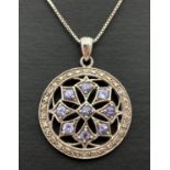 A modern design pierced work circular shaped pendant set with tanzanite's & diamonds. On an 18" fine