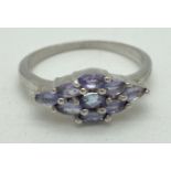 A silver dress ring set with 9 oval cut tanzanite stones in a diamond shaped mount. Inside of band