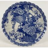 An Oriental blue & white ceramic charger with scalloped rim and floral basket design. Decorated with