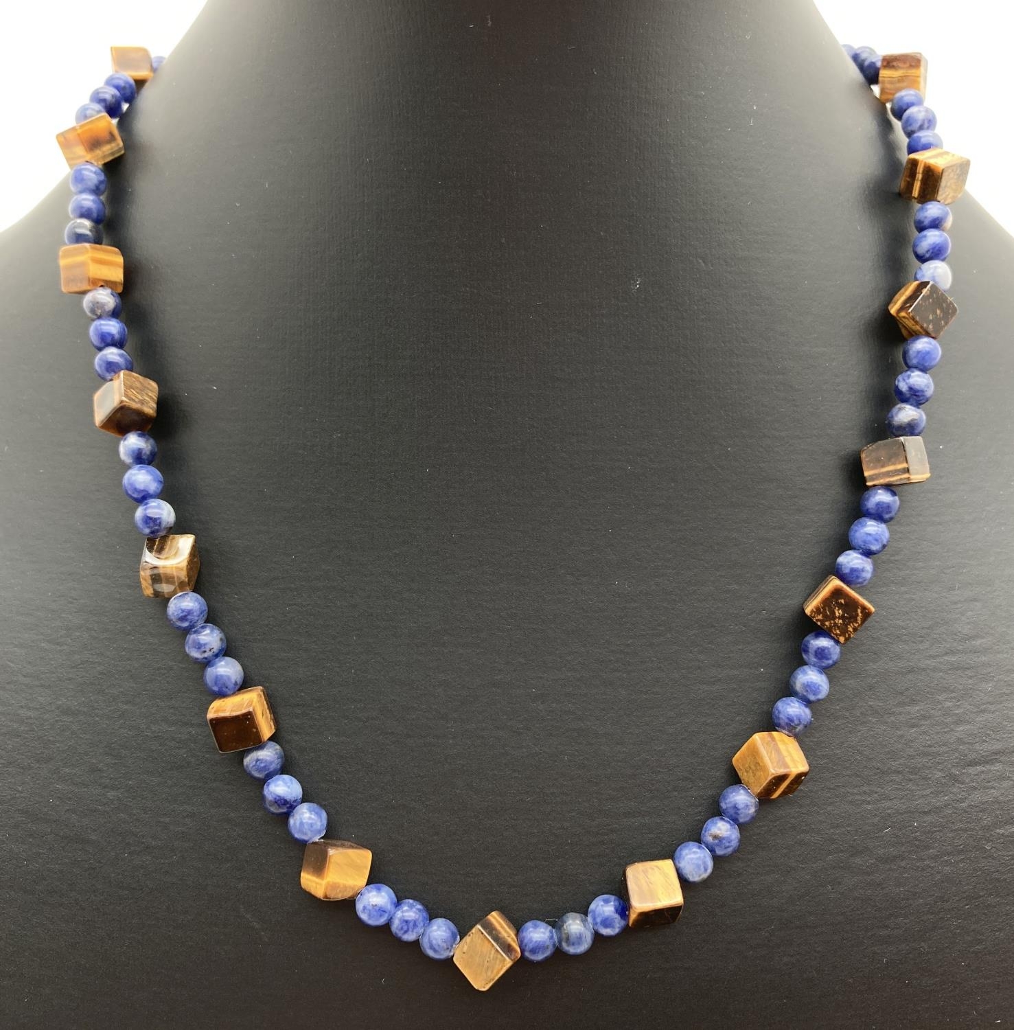A lapis lazuli and square shaped tigers eye beaded necklace with flower shaped T bar clasp.