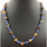 A lapis lazuli and square shaped tigers eye beaded necklace with flower shaped T bar clasp.