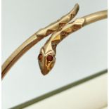 A 9ct gold thin bangle with snakes head & tail detail set with small garnet stones. Approx. 6.5cm