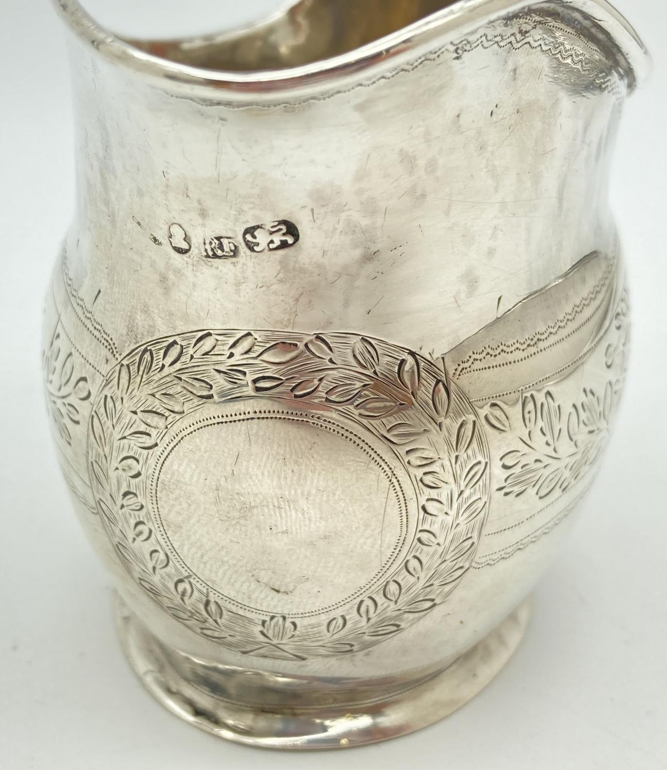 A Georgian silver cream jug with engraved floral banded design. Featuring a wreathed circular shaped - Image 2 of 4