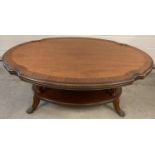 A reproduction oval shaped occasional table with shaped top and undershelf. Brass claw shaped feet