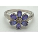 A flower design silver dress ring set with tanzanite's and diamonds. 7 central small cut diamonds