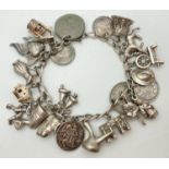 A vintage charm bracelet with a collection of silver & white metal charms & coins. Charms to