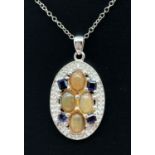 A modern design oval silver pendant set with orange opal and iolite. By The Genuine Gem Company,