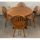 A modern light wood circular dining table and 4 chairs. 2 sectional draw leaf table with central