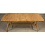 A Mid Century Ercol blond coffee table with splayed legs and spindled undershelf. With square blue