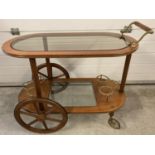 A reproduction dark wood bar cart with glass insets to top and undershelf. Brass detail to