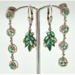 2 pairs of silver emerald set drop style earrings. A pair of floral design drops each set with 6