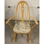 A modern Ercol rocking chair with hooped back carved swan design. Floral design chair cushion and