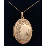 A 9ct gold oval shaped locket on an 18" 9ct gold fine curb chain. Locket has floral detail to