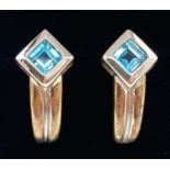 A pair of 9ct duo coloured gold stud earrings set with square cut blue topaz stones. Fully