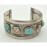 An Egyptian silver cuff bangle with carved stone set scarab beetle detail. Worn hallmarks to outer