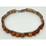A silver and amber bracelet with 8 jointed links and lobster claw clasp. Each link is set with 3