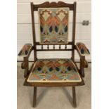 An Edwardian folding campaign chair with shaped and carved top and turned spindle detail to back.
