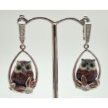 A pair of silver enamelled brown owl and flower detail drop style earrings. Small clear stones set