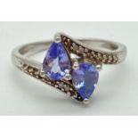 A 9ct white gold, tanzanite and diamond ring with a twist design setting. 2 teardrop shaped