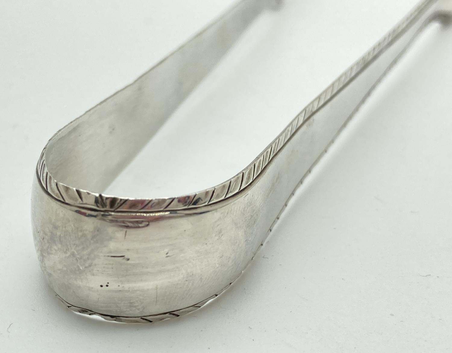 A pair of Georgian silver sugar tongs with feather edged detail. Stamped to inner spoon bowls with - Image 4 of 4