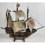 A vintage 1930's wooden model ship with painted leather details and sails. Engraved brass