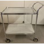 A retro aluminium framed 2 tier tea trolley with handle to one side. Black rubber wheels and grey