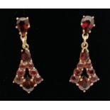 A pair of 9ct gold and garnet chandelier drop earrings, with butterfly backs. Each has 8 garnets