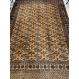 A large ochre coloured Indian style rug with brown, black and cream colours in a geometric design.