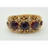 A Victorian 15ct gold ring with decorative mount set with garnets and seed pearls. Engraved detail