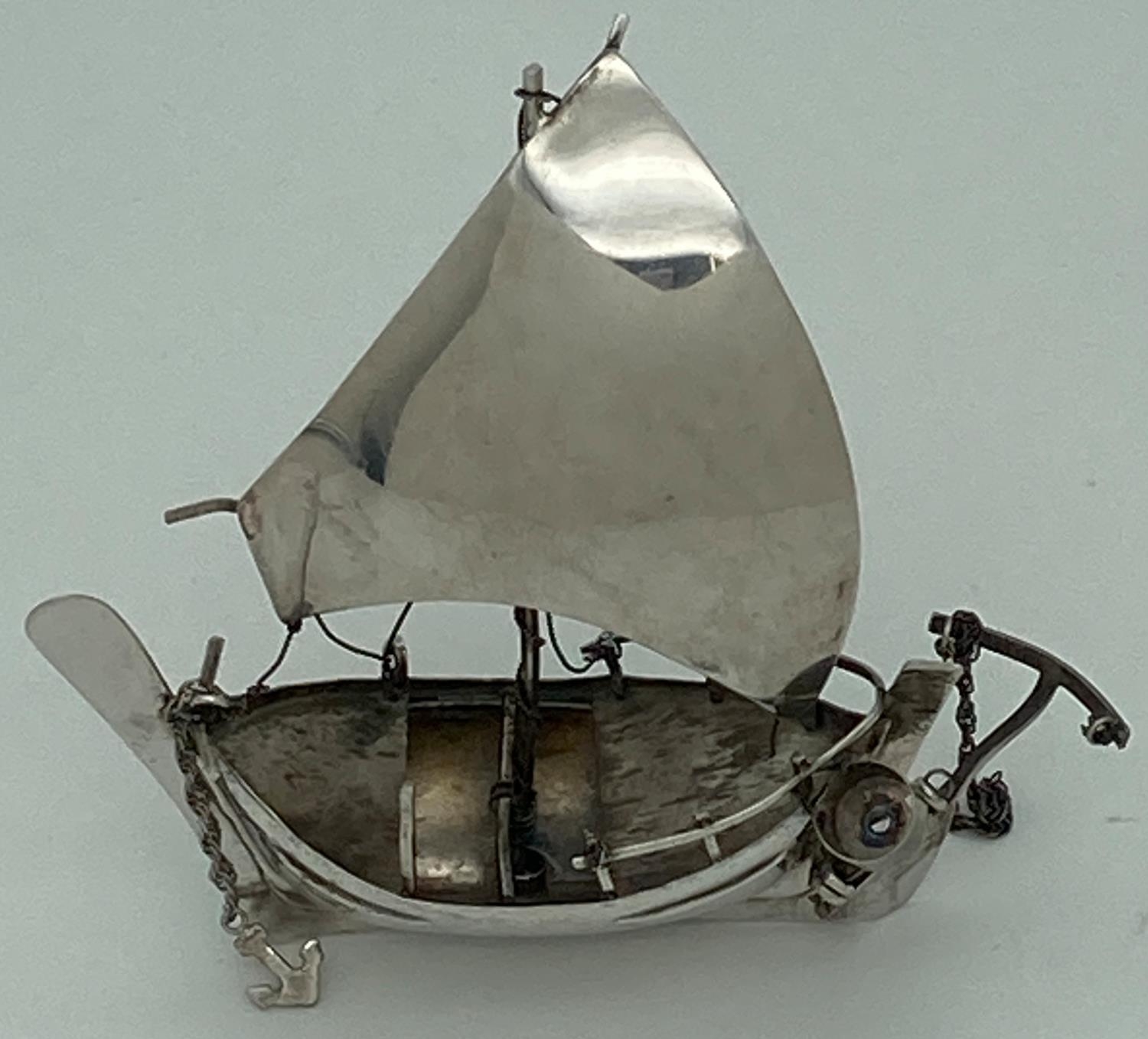 A vintage silver miniature sailing boat figurine with rudder, anchor and bailing bucket. Marked