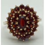 A 9ct gold dress ring set with a large cluster of garnets, fully hallmarked inside band. Ring size