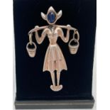 A silver stone set brooch in the form of a Dutch girl with hanging bucket pendants. Set with blue