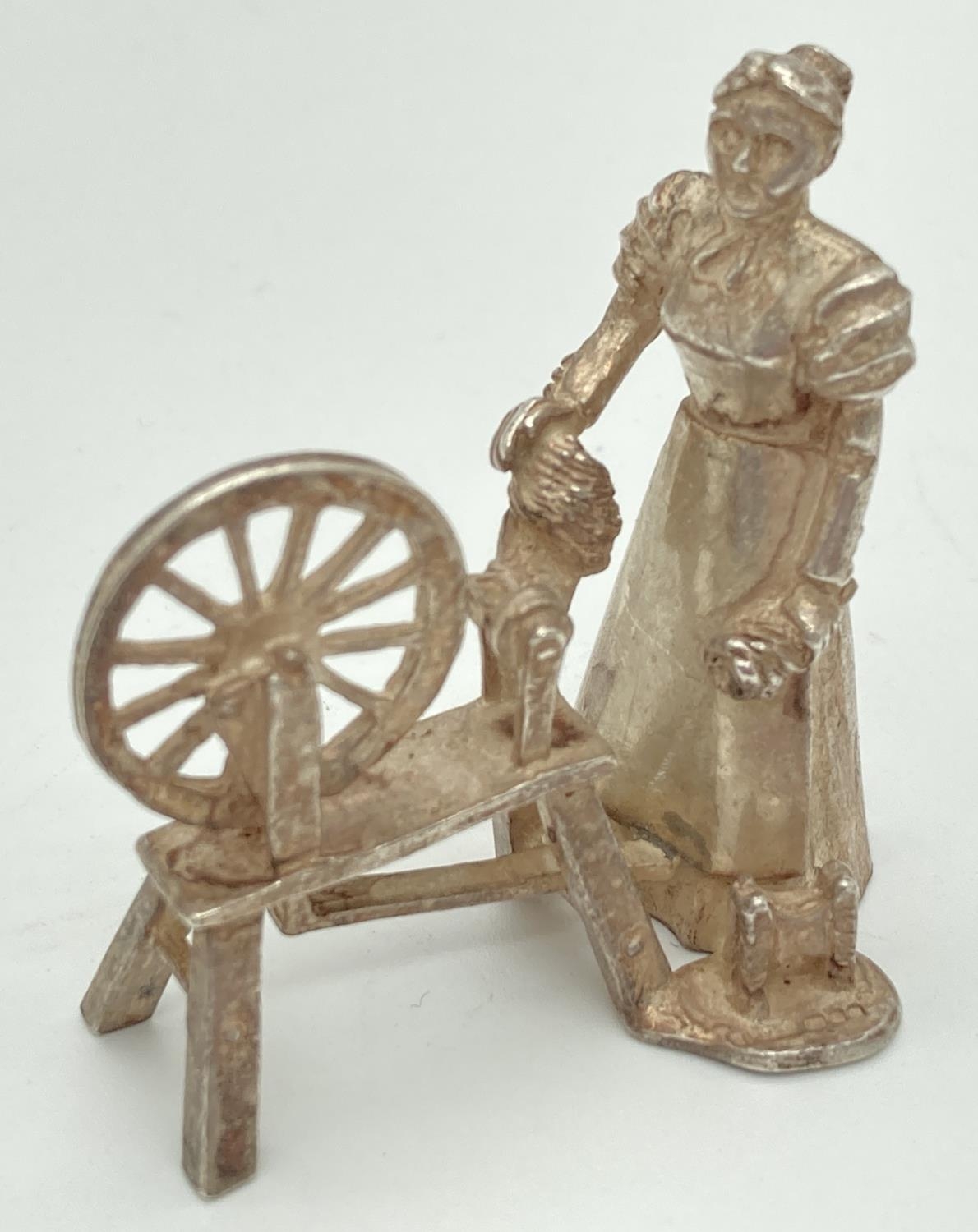 A vintage silver miniature model of a woman working a spinning wheel. Fully Hallmarked to base for