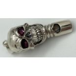 A modern 925 silver whistle in the form of a skull with red stone set eyes & hanging bale. Marked
