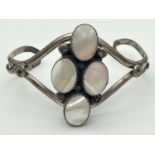 A white metal open style cuff bangle set with 4 oval pieces of mother-of-pearl.