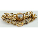 A decorative open work design yellow metal brooch set with rough cut diamonds. Pin back fixing