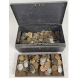 A vintage black metal cash tin containing a collection of vintage British and foreign coins. To
