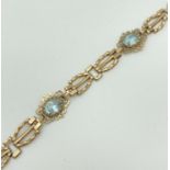 A 7" 9ct yellow gold decorative link bracelet set with 4 oval blue topaz stones. With spring ring