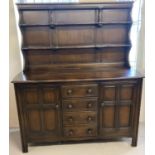 A vintage Ercol dark wood triple dresser with 2 door, 4 drawer base. With plate rack shelving top