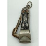 An antique white metal novelty cigar cutter in the form of an owl. With glass eyes and hanging bale.