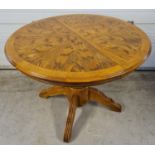 A vintage circular light wood dining table with central turned pedestal base. 4 feet with channelled