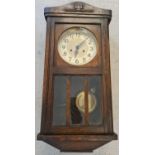 A vintage dark wood cased wall clock with glass panelled door. Complete with key & pendulum, for
