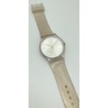 A unisex Swatch watch IS04 with brushed silver effect face and silver glitter silicone strap. Face