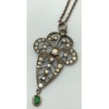 An Art Nouveau 800 silver pendant set with clear stones and emerald hanging pendant. On a vintage