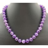A 16" amethyst beaded necklace with silver tone magnetic clasp. Each bead approx. 1cm diameter.