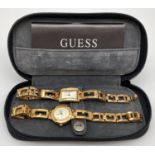 2 womens Guess wristwatches with gold tone cases and bracelet straps, complete with zipped case