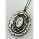A late Victorian silver oval shaped locket with engraved letter "E" to front & inscription to